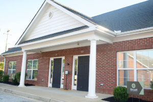Brick medical office building with white columns and an iTrust sign at 123 Commons Way
